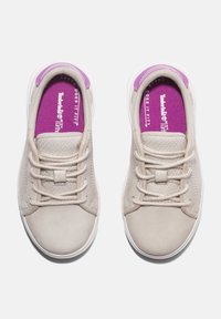 Ljusbeiga sneakers med en texturerad finish, snören och en lila accent på innersulorna. Har en rund tå och en vit sula.