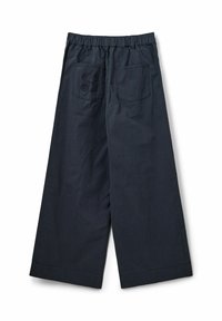 Baumwoll-Hose mit weitem Bein in dunkelblau, mit elastischem Bund und zwei Gesäßtaschen, von denen eine ein gerundetes Logo-Muster aufweist.