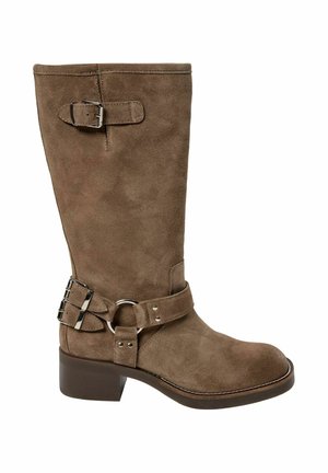 Botte mi-mollet en daim marron avec un talon bas et épais, ornée de deux boucles en argent et d'une lanière avec un anneau métallique rond sur le côté.