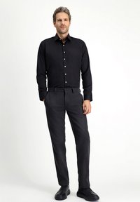 Czarna, zapinana na guziki koszula z długim rękawem, zestawiona z ciemnoszarymi, dopasowanymi spodniami oraz czarnymi butami, wykonana z gładkiej tkaniny o klasycznym kroju.