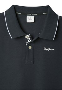 Tamsiai mėlyna polo marškinėliai, pagaminti iš tekstūrinio audinio, su balta siuvinėta logotipu, dryžuotais apykaklės akcentais ir dviem mygtukais.
