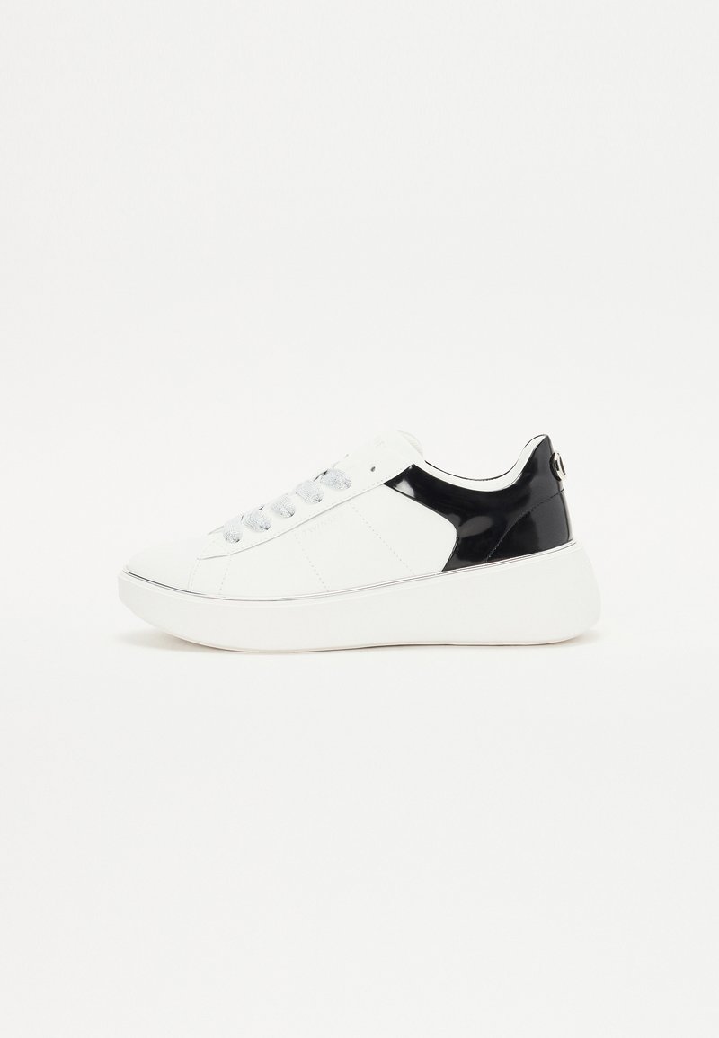 Fehér sneaker fekete lakk részletekkel, sima textúrával, kerek orral, ezüst fűzőlyukakkal és fehér platform talppal. Egyszerű, modern dizájn.