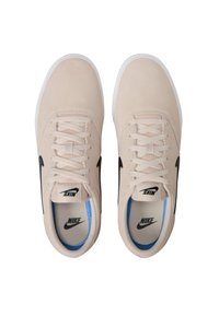 Zapatillas de ante beige con suelas blancas, con el logo de Nike en negro y acentos en azul claro por dentro. Presentan un diseño clásico de cordones.