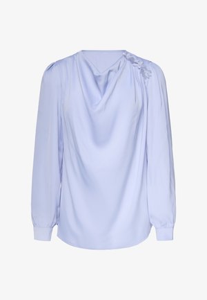 Lichtblauwe blouse met lange mouwen, gedrapeerde halslijn, bloemenapplicaties op één schouder, losse pasvorm en manchetten met knopen.