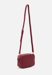 Borsa a tracolla rossa in finta pelle con forma rettangolare, tracolla regolabile e hardware dorato. Tessuto liscio e chiusura con cerniera sulla parte superiore.