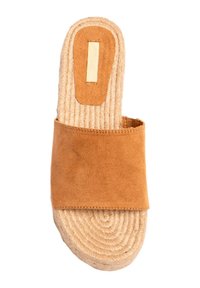 Sandalia deslizante de ante color tostado con una correa ancha, suela de yute y un acento rectangular en la parte superior. Diseño de suela texturizada y plana.