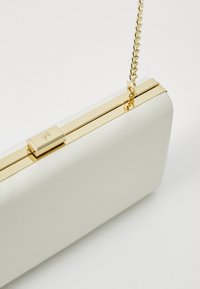 White rectangular clutch with glossy finish, gold hardware, and a chain strap. Clasp closure on the top with a sleek design.