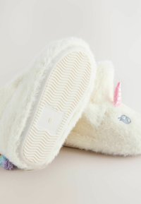 Weiße, flauschige Hausschuhe mit einer strukturierten Sohle, die ein Einhorn-Design mit einem rosa Horn und bunten Bommelakzenten aufweisen. Größe 6 angegeben.