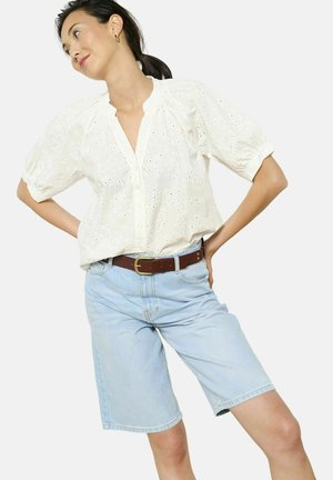 White embroidered top with short puff sleeves, button-down front, paired with light blue denim shorts and a brown belt. Plain background.