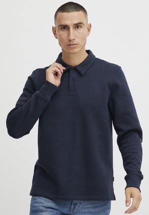 Marineblauwe poloshirt met lange mouwen, kraag, een knoopsluiting en ribgebreide boorden. De stof ziet er zacht uit met een gladde textuur.