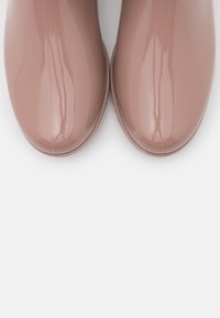 Bottines roses brillantes avec un bout rond et une surface lisse et brillante. Design minimaliste sans accents ni motifs supplémentaires.