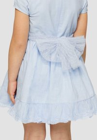 Helles blaues Baumwollkleid mit kurzen Ärmeln, einem Rüschensaum und Spitzendetails; auf der Rückseite befindet sich eine große, durchsichtige Schleife.