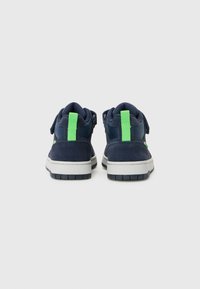 Navy blue sneakers with a suede and synthetic upper. Features a bright green heel tab and detailed textured outsole.