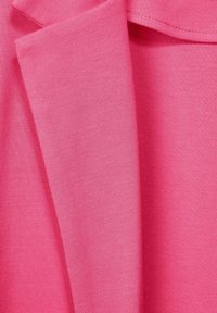 Vaaleanpunainen kangas, jossa on sileä, venyvä pinta ja lievä kiilto. Materiaalikerrokset limittyvät, paljastaen siistit reunat ja tasaisen värin.