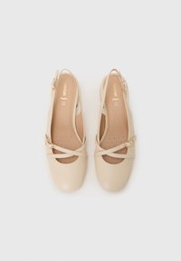 Beige läderslingback-skor med rund tå, korskonstruktion och guldfärgad spänndetalj. Vadderad innersula med perforeringar.
