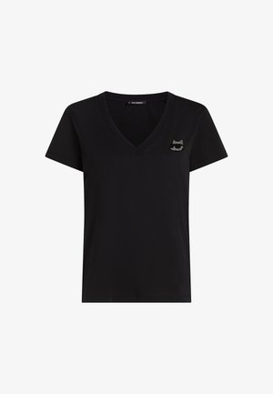 Musta puuvillainen V-pääntie t-paita lyhyillä hihoilla, jossa vasemmassa rinnassa pieni, koristeellinen kissalogot. Silkkinen rakenne.