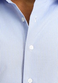 Camicia a righe blu e bianche con colletto classico, dotata di bottoni bianchi e una texture di tessuto leggera e liscia.