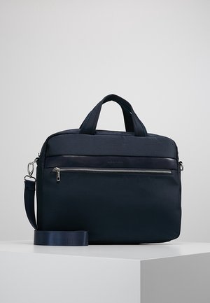 Granatowa torba na laptop z podwójnymi uchwytami, przednią kieszenią na zamek i odpinanym paskiem na ramię, spoczywająca na białej powierzchni.