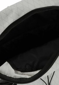 Zaino di medie dimensioni con un'esterno bianco texturato caratterizzato da un motivo a diamante, apertura con zip e foderato internamente di nero.