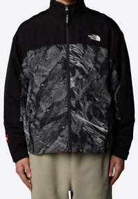 Svart zip-up jacka med ett grafiskt mönster i nyanser av grått, med hög krage och kontrasterande ärmdetaljer. Texturerad tyg.