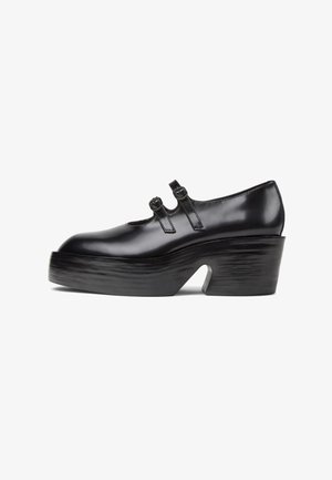 Zwarte gepatineerde leren Mary Jane schoen met twee gespsluitingen, dikke plateauzool en lage blokhak op witte achtergrond.
