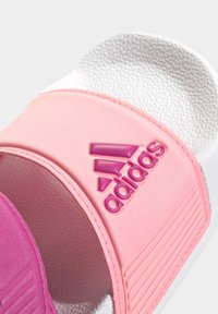 Adidas sandále na nosenie, s mäkkým ružovým popruhom s embossovaným logom, textúrovanou stielkou a kontrastnou bielou podrážkou pre pohodlie.
