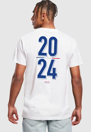 Hvit bomulls t-skjorte med store blå tall "2024" og en rød linje på baksiden, med en liten logo under. Korte ermer og rund hals.