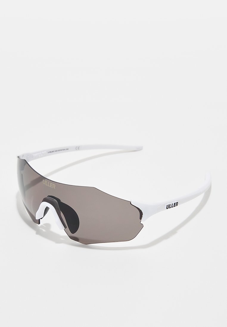 Lunettes de sport blanches avec une grande lentille sombre, mettant en avant un design enveloppant et une ligne de sourcil prononcée ; présente un logo de marque.