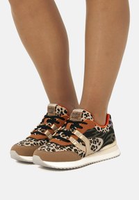 Sneaker mit Leopardenmuster, braunen Wildlederakzenten, goldenen Streifen und schwarzen Schnürsenkeln. Verfügt über eine gepolsterte Sohle und ein lebhaftes oranges Innenfutter.