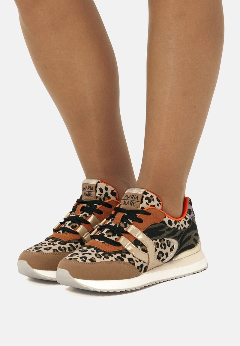 Sneaker mit Leopardenmuster, braunen Wildlederakzenten, goldenen Streifen und schwarzen Schnürsenkeln. Verfügt über eine gepolsterte Sohle und ein lebhaftes oranges Innenfutter.