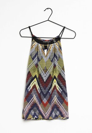 Top à bretelles spaghetti avec un motif en zigzag jaune, rouge, marine et blanc. Tissu léger, avec un détail en forme de goutte à l'encolure.