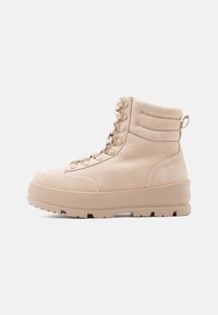 Beige lace-up potītes, izgatavotas no gludas ādas, ar mīkstinātu apkakli, platu zoli un diskrētu aparatūru. Rakstaina virsma.