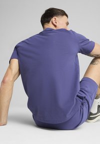 Lilla kortærmet skjorte med en afslappet pasform, parret med matchende shorts, der viser en glat tekstur og et enkelt design.