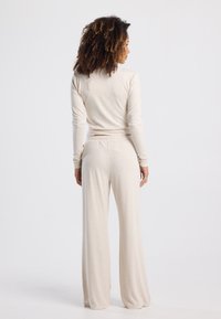 Beige long-sleeve top and wide-leg pants made of soft, lightweight fabric. Smooth texture with a relaxed fit. No notable patterns or accents.