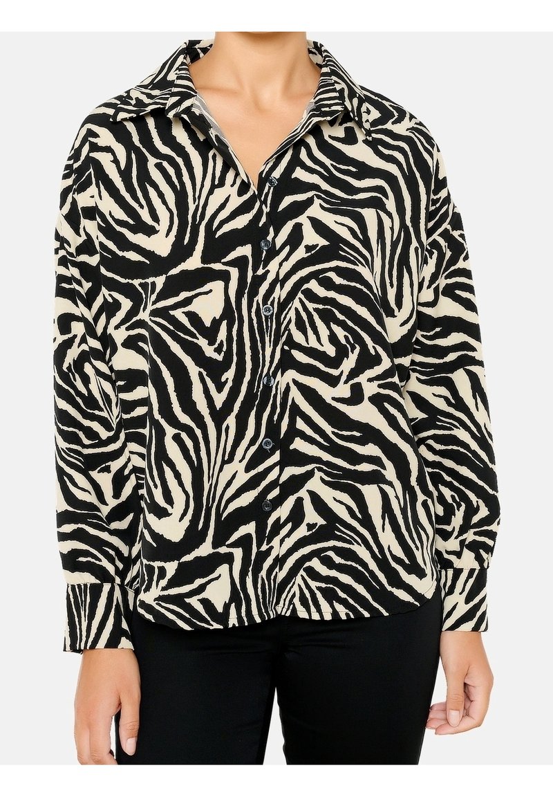 Chemise boutonnée à motif zèbre noir et crème, dotée d'un col, de manches longues avec poignets boutonnés, et d'une coupe décontractée.