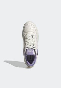 White leather sneaker with light purple accents, perforated toe box, and a fabric tongue. Features flat laces and a soft inner lining.