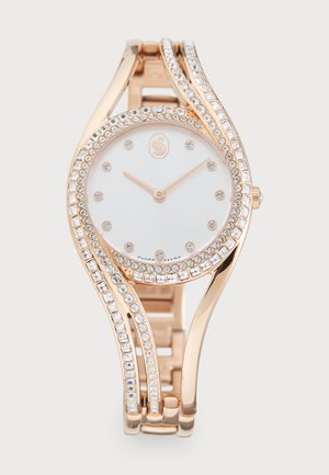 Roségoldene Uhr mit einem glänzenden weißen Ziffernblatt, verziert mit kleinen Kristallen entlang der Lünette und des Armbands, das ein Wellenmuster zeigt.