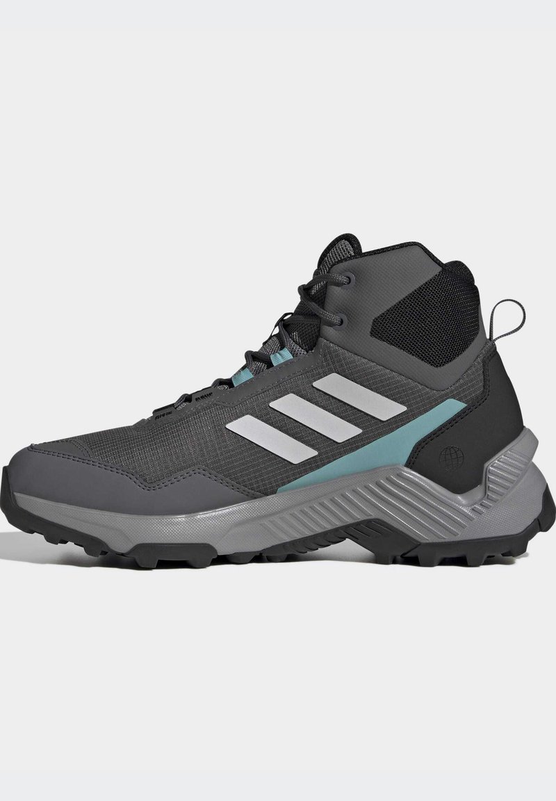 Szare, wysokie buty trekkingowe z siateczki i materiału syntetycznego, z trzema białymi paskami, akcentami w kolorze teal oraz teksturowaną podeszwą dla lepszej przyczepności.