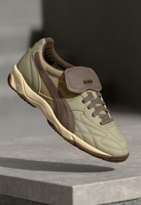 Hellgrüne Leder-Sneaker mit braunen Akzenten, strukturiertem Obermaterial, klassischem Design, gepolstertem Kragen und Gummisohle.
