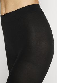 Μαύρες κολάν με λείο, ελαστικό υλικό. Υψηλή ελαστική ζώνη, εφαρμοστή σχεδίαση, αδιάσπαστη εμφάνιση και ελαφρύ ύφασμα.