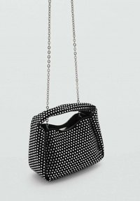 Zwarte handtas met zilveren studs en kettingriem, met een ronde bovenkant, zachte textuur en een ruime open binnenkant.