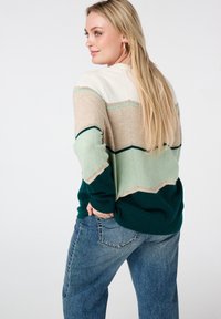 Pull en tricot avec des rayures variées en crème, beige, vert menthe et vert foncé. Il présente une coupe décontractée et des poignets côtelés.