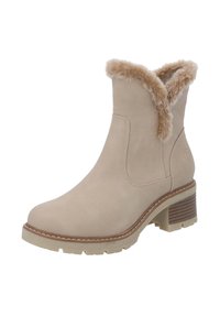 Beige suède enkellaars met een kunstbont rand aan de bovenkant, een contrasterende lichte zool en een gestapelde, textuur-rijke hak.