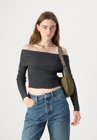 Top crop off-shoulder cinza escuro com textura, mangas longas, combinado com jeans de ganga azul de cintura alta. A bolsa é verde-azeitona com uma alça.