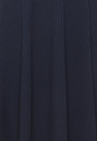 Tummansininen laskostettu kangas, jossa on uurrettu pinta, ja pystysuorat raidat, jotka kulkevat saumoja pitkin. Ei näkyvää metalliosaa tai koristeita.