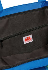 Interno di una borsa a tracolla blu, con una fodera in tessuto nero liscio e un comparto con cerniera. Include un'etichetta bianca con un logo rosso.