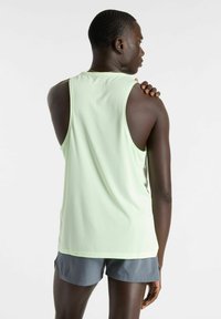 Light green, sleeveless athletic tank top with a textured finish. Pairing with gray shorts. Minimalist design, suitable for active wear.