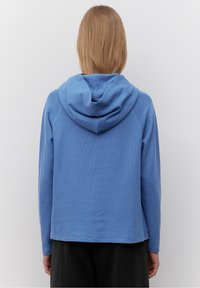 Blå huva sweatshirt med texturerad tyg, avslappnad passform och långa ärmar. Båda sidorna av fållen är något rundade bakåt.