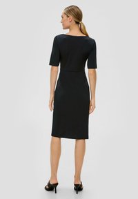 Robes noires midi avec des manches courtes, texture lisse et taille cintrée. Dotée d'un col rond, elle tombe juste en dessous du genou.