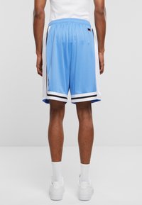  pantaloni scurți de baschet din plasă albastră cu panele laterale albe, dungi negre și un brâu elastic. Purtați cu sneakers albi și șosete.